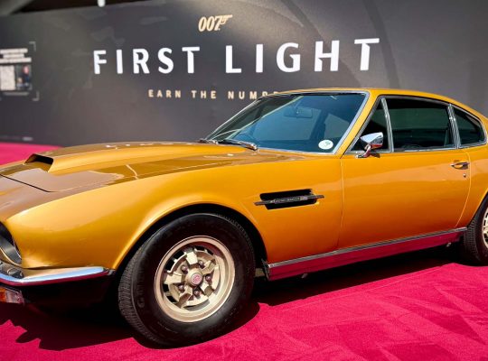 Yellow Aston Martin DBS from 007: First Light on display at IO Interactive’s Gamescom 2025 booth, showcased as part of the Bond vehicle lineup.
