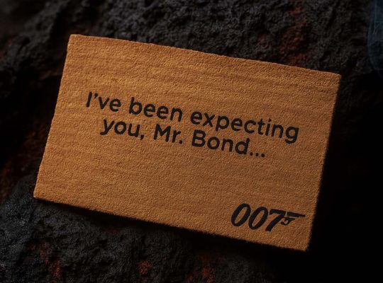 Official James Bond 007 doormat with the quote “I’ve been expecting you, Mr. Bond…” placed on a rugged lava stone ground.