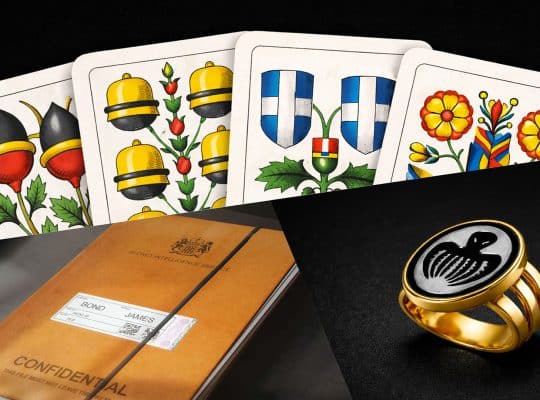 Confidential MI6 file for James Bond, Swiss-German Jass playing cards, and a gold Spectre ring featuring the iconic octopus symbol in 007 First Light
